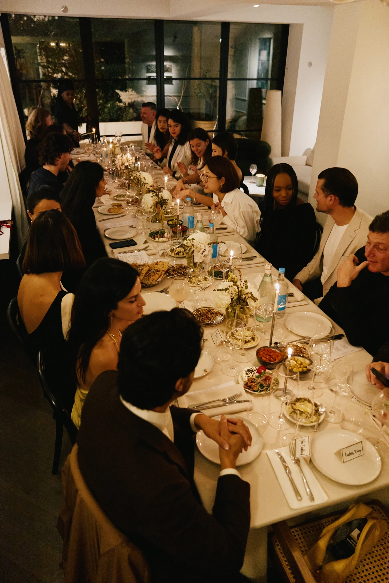 Guests seated along the candlelit dining table, seen from one end.