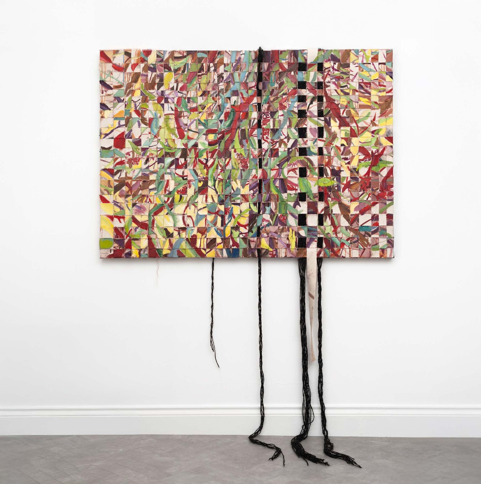 A woven painted canvas with long black strands of goat hair hanging to the floor.