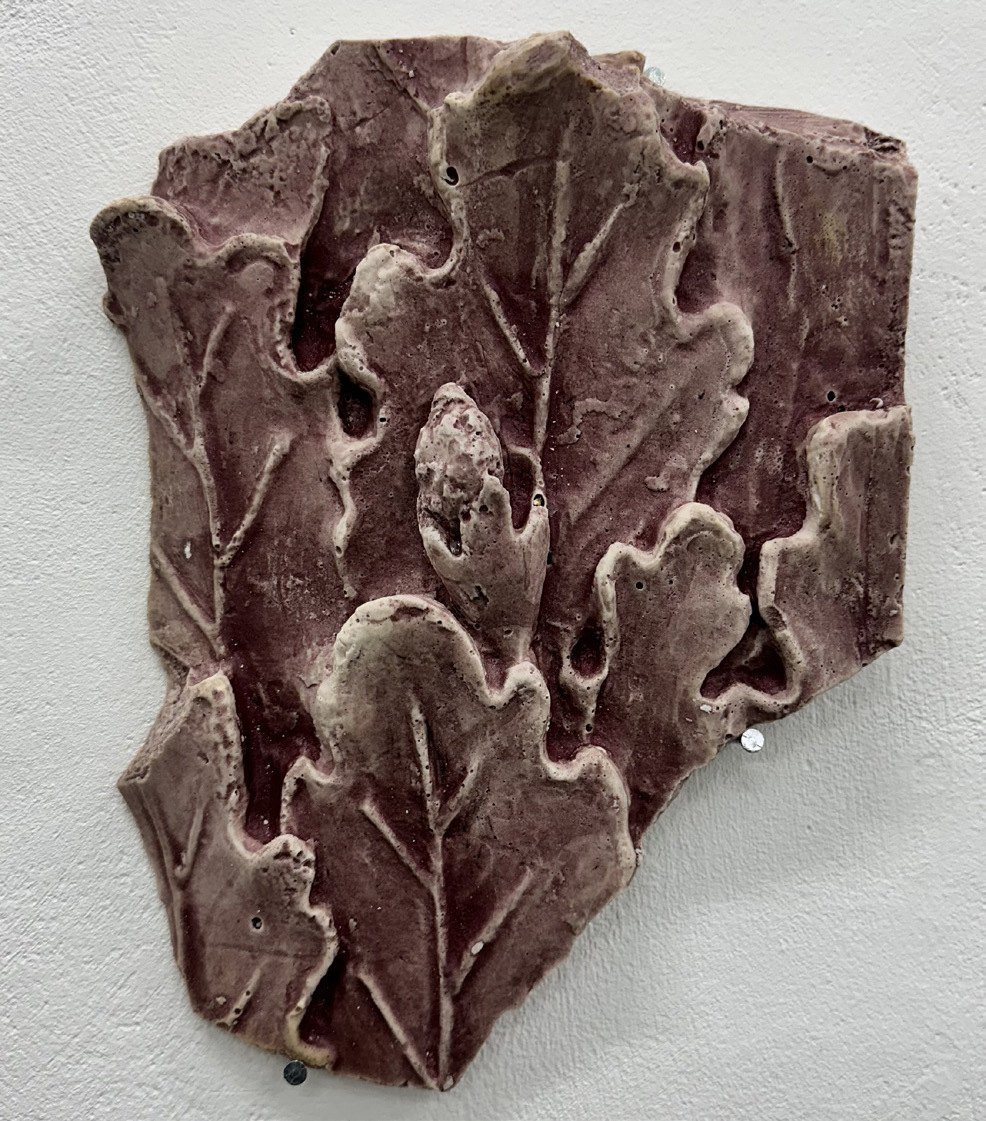 A cast plaster relief of poppy leaves stained deep purple.