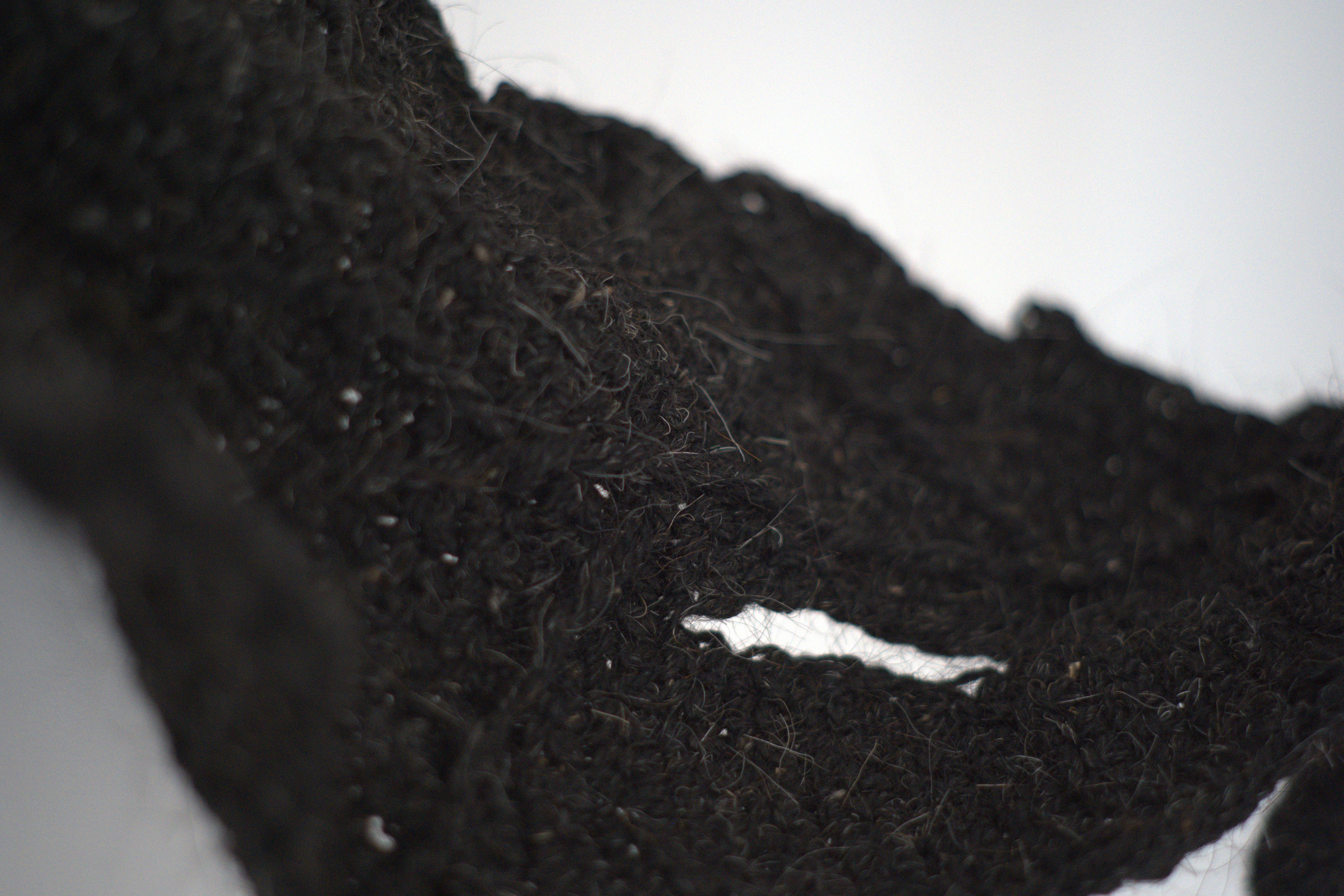 Close-up of black fibres and stitching in a leaf-shaped textile form from Stasis.