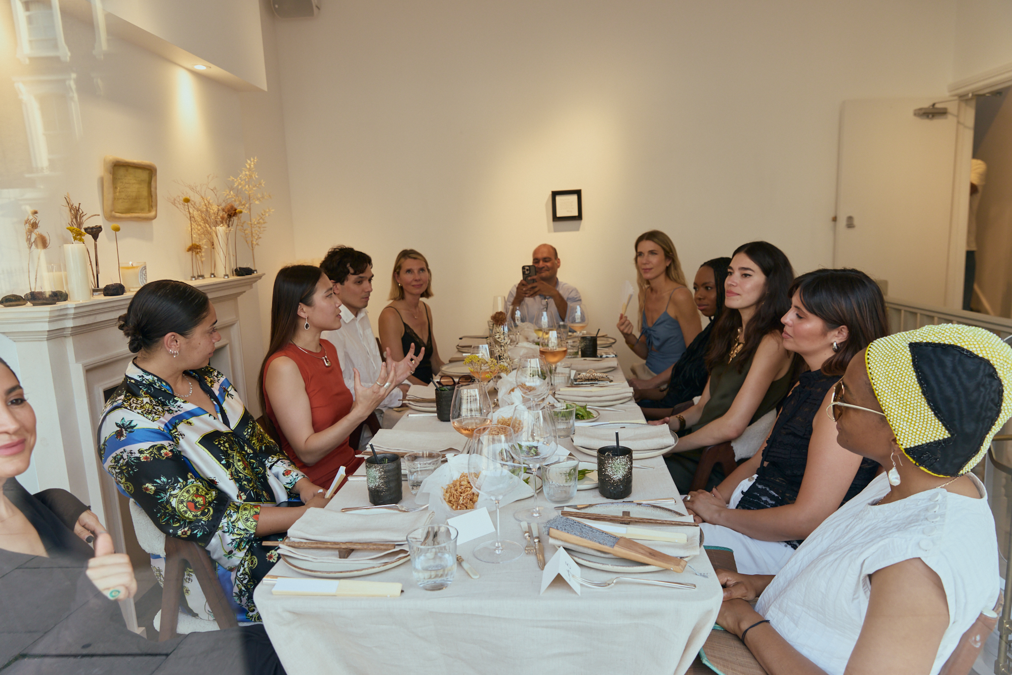 Guests gathered around a long, linen-covered table in the gallery, with artworks on the walls.