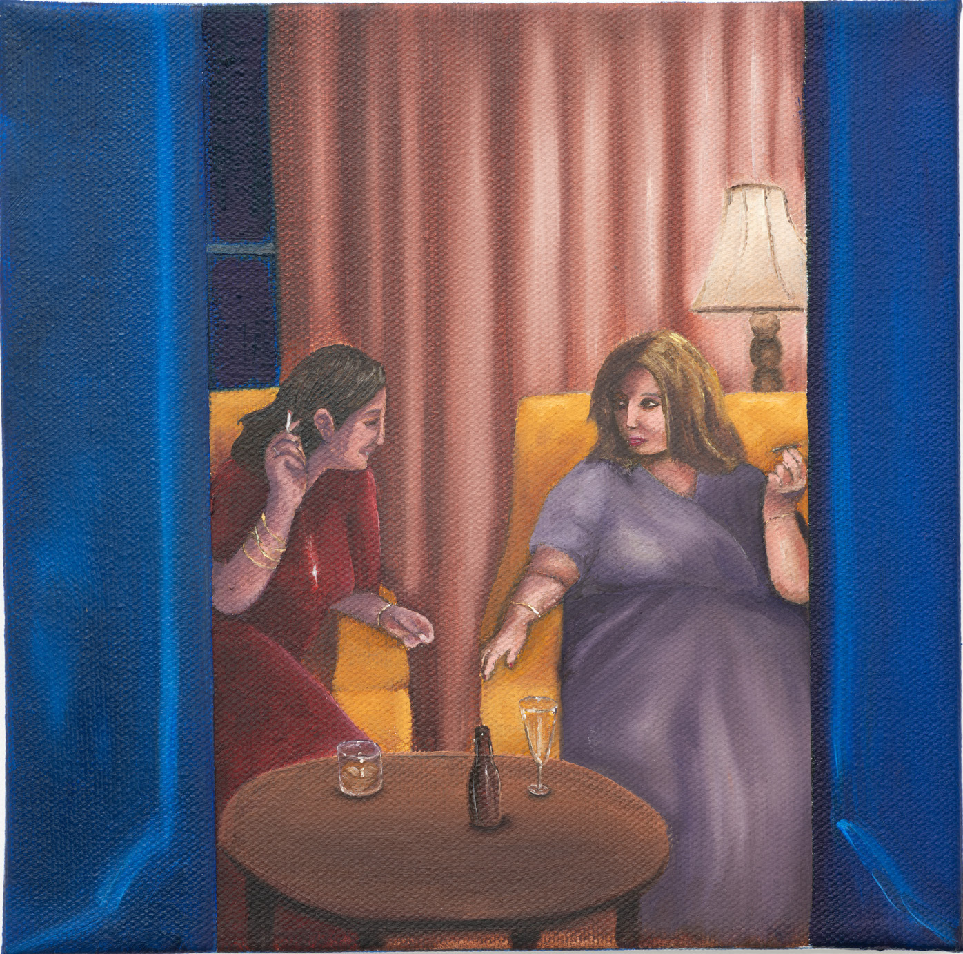 Two women speaking across a small table beside blue curtains and a lamp.