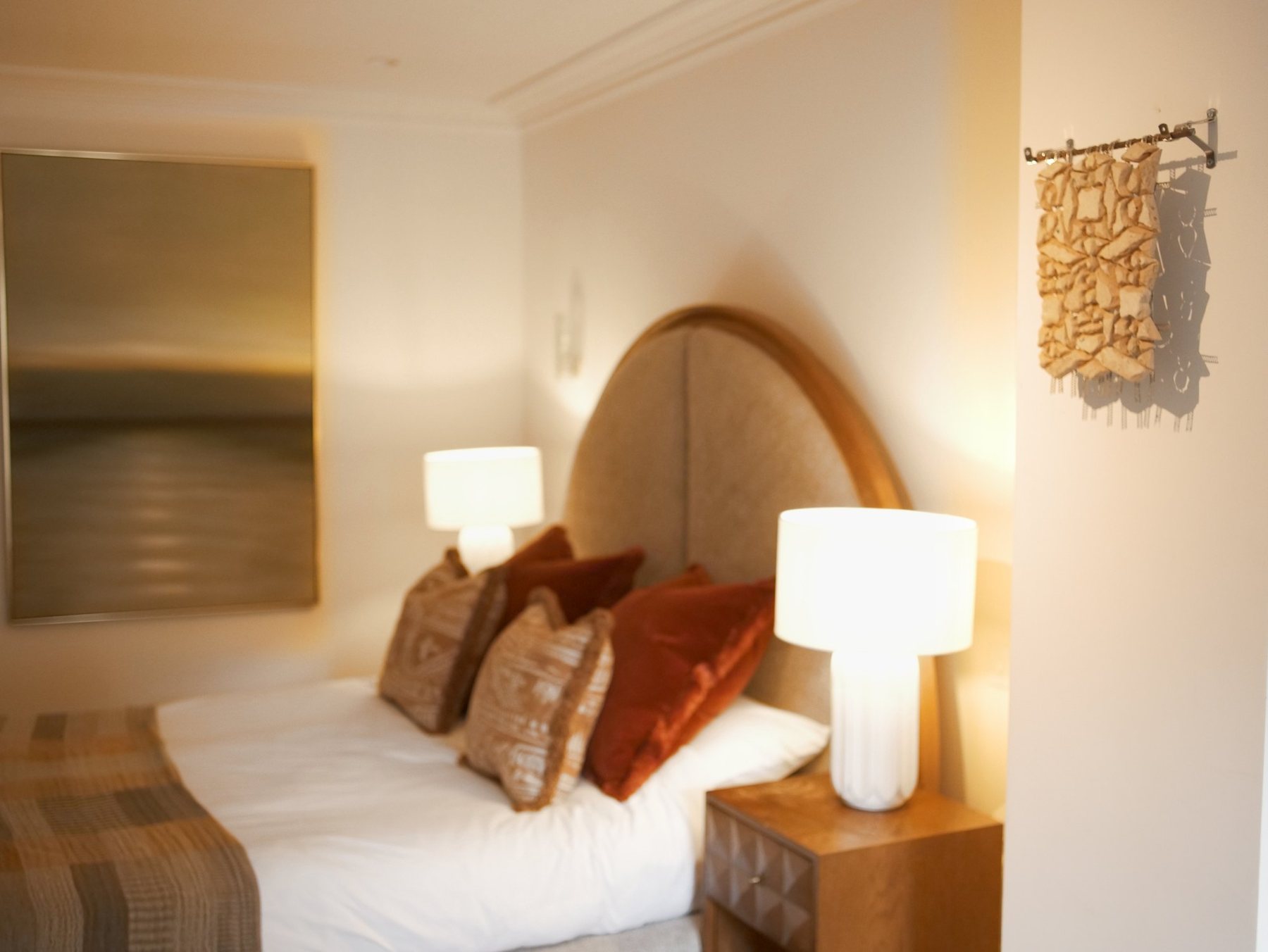 The bedroom: a bed with cushions and lamps, and the tile-back panel hanging on the wall to the right of the bed.