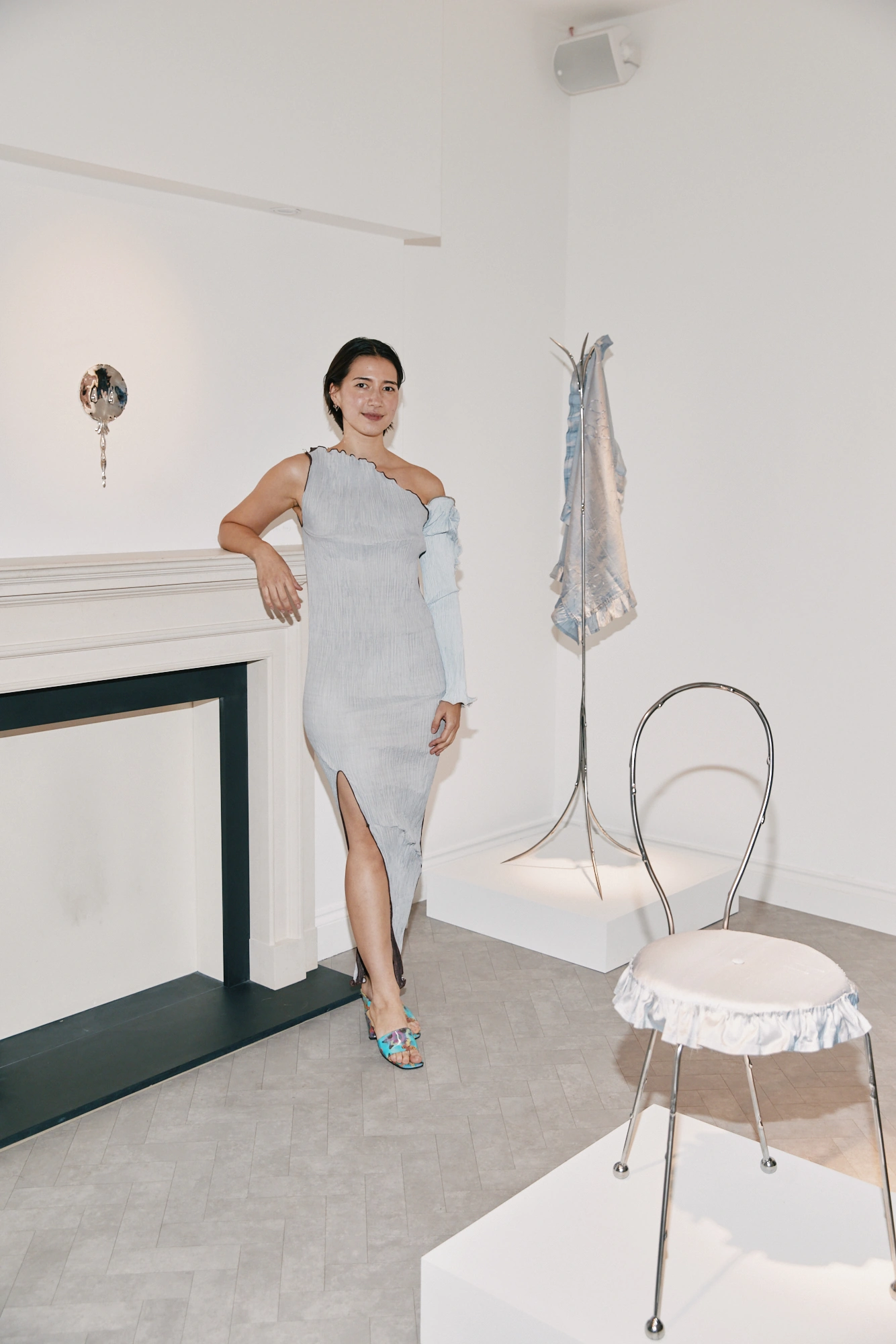 A guest beside the fireplace and silver sculptures at the exhibition opening.