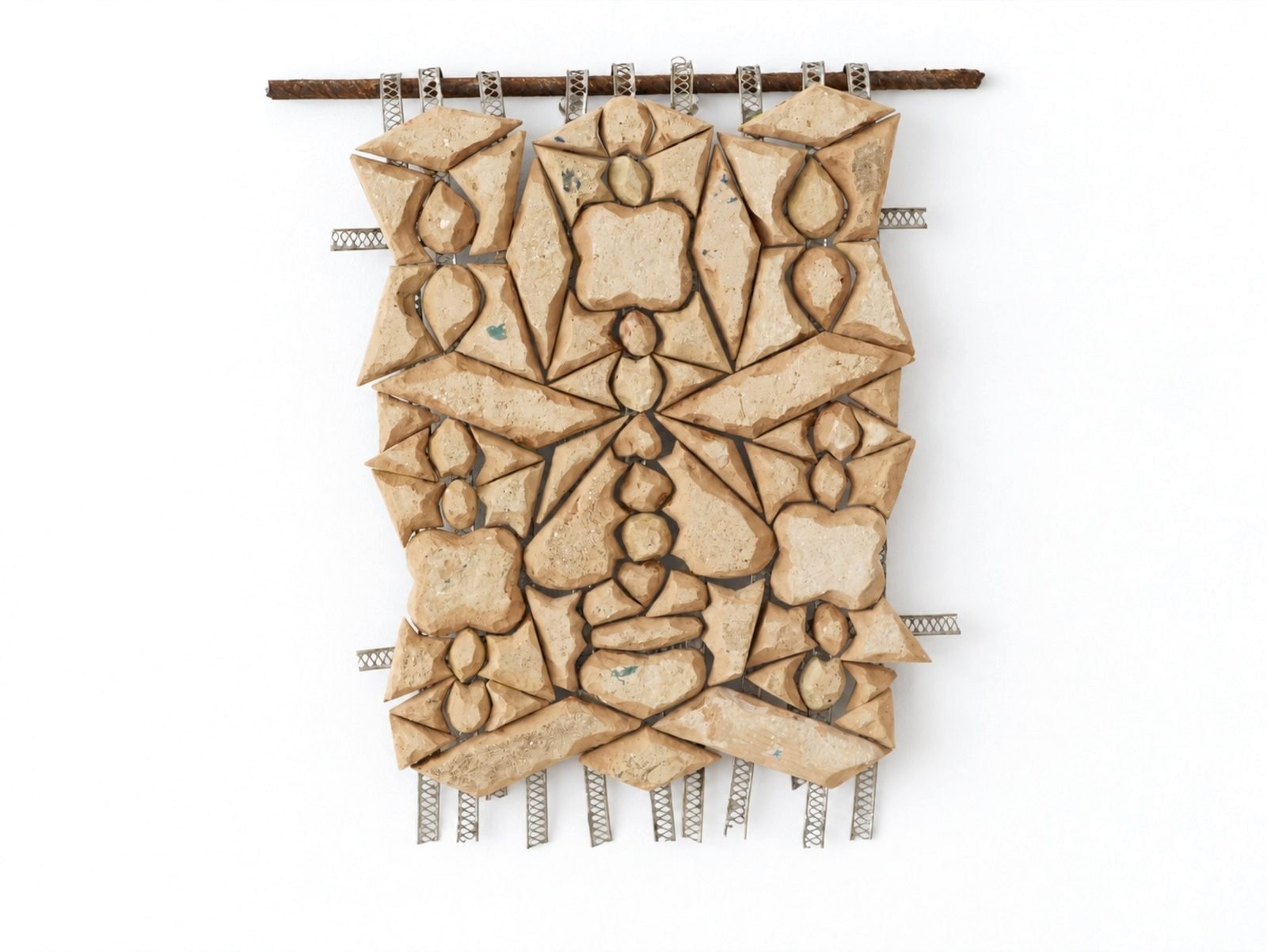 The unglazed backs of cut zellige tiles, joined with metal wire into a hanging panel.